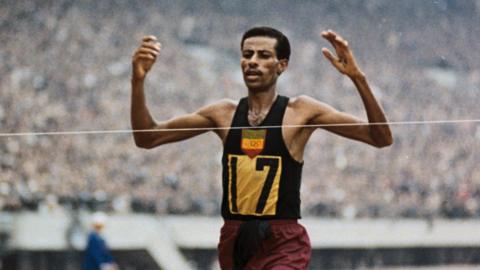 Abebe Bikila in running vest at the finish line of a marathon