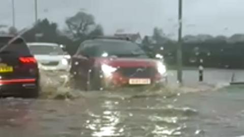 Cars driving through flood water.