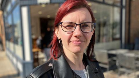 A woman with red hair in a leather jacket