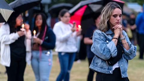 Community members pray and hold candles while holding umbrellas, at a vigil for the victims in Winder, Georgia on 6 September