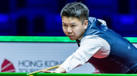 China's Zhou Yuelong prepares to play a shot against Ali Carter in their World Grand Prix quarter-final in Hong Kong
