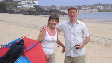 Christopher Brailsford and his wife standing next to a tent on a beach in Cornwall.