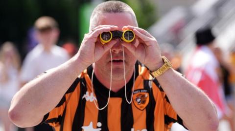 A Hull City fan with some binocculars on Wembley Way 