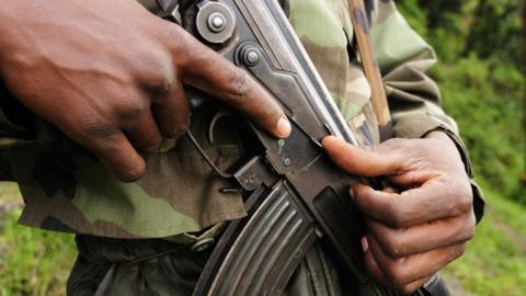 An anonymous man in fatigues holding a gun.