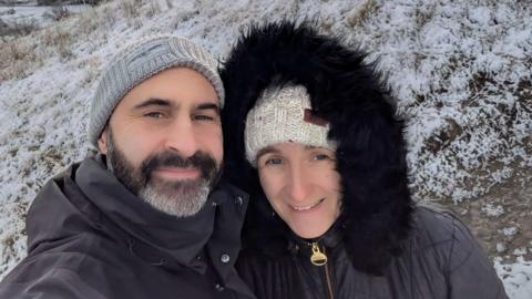 A man and woman in a snow-covered outdoor scene.