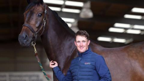 Tom McEwen standing in the stable with horse JL Dublin