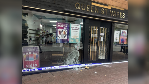 The front of Queen Street Vapes shop with smashed window and police tape