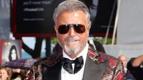 Catalin Botezatu wears an elaborated black tux finished with read and gold thread. 