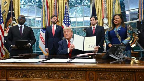 President Donald Trump holds a letter addressed to Congolese President Félix Tshisekedi congratulating him on the peace agreement with Rwanda during a meeting with Democratic Republic of the Congo Foreign Minister Thérèse Kayikwamba Wagner (R) and Rwandan Foreign Minister Olivier Nduhungirehe (L) in the Oval Office of the White House in Washington, DC, on June 27, 2025