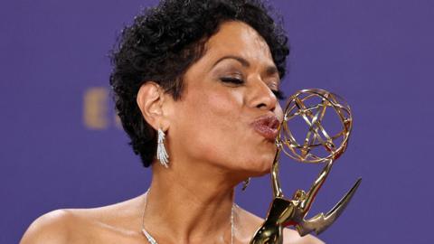 Liza Colon-Zayas kissing her Emmy Award