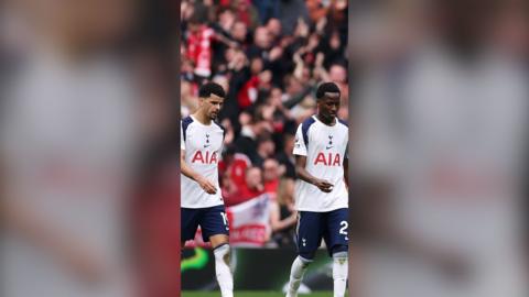 Two Spurs players walk across the pitch with their heads slightly bowed