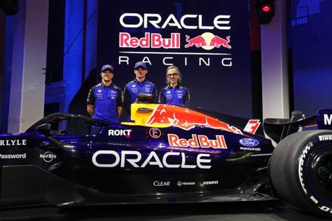 Isack Hadjar, Max Verstappen and team principal Laurent Mekies stand behind the new Red Bull car during the Red Bull Racing season launch at Michigan Central Station