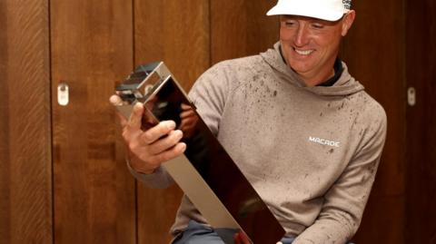 Alex Noren looks at the BMW PGA Championship trophy