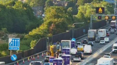 Roadworks and a lane coned off with heavy traffic on the motorway. 