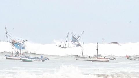 Several fishing boats upended by a huge wave