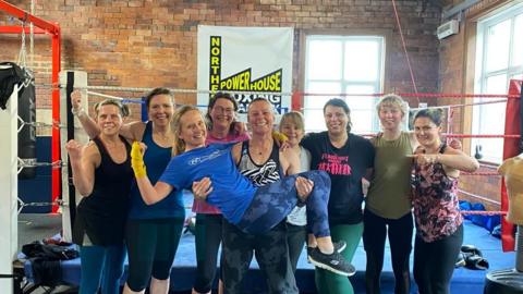 Northern Powerhouse Boxing Club team in front of a boxing ring