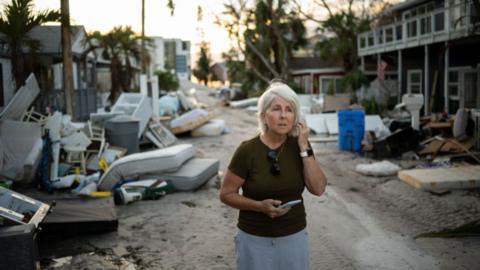 Amy Ace Lance pauses in the street in front of her home in Treasure Island, Fla. on October 10, 2024