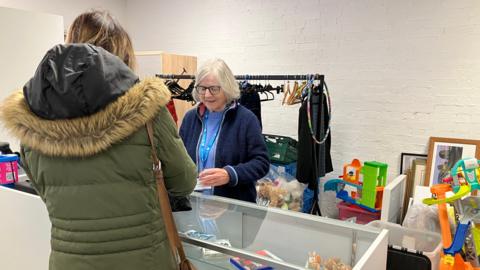 A woman serving another woman at a charity shop