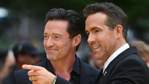 Hugh Jackman and Ryan Reynolds pose on a red carpet 