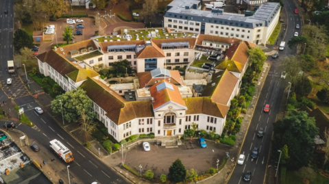 A bird's eye view of the Poole Civic Centre, a two-storey art deco building bordered by roads either side of it.