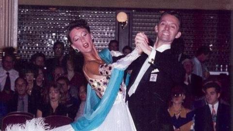 An old grainy picture of a man and woman doing ballroom dancing in front of a crowd.