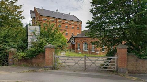 A large brick building with an annex on the side. 