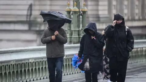 A group of people are battered by strong winds as they cross Westminster Bridge in London, United Kingdom. 