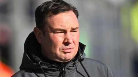 Morecambe boss Derek Adams looks on