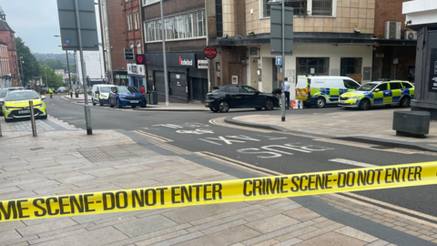 Yellow police tape seals off Foundry Street with police officers inside the cordon