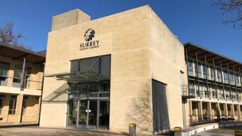 Surrey County Council headquarters building. The sun is shining in a blue clear sky.