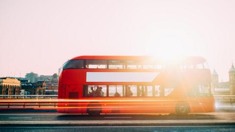 A double decker red London bus. There are lines of light indicating it is moving forward.