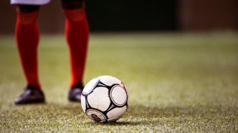 A football player stands behind a ball