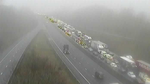 A traffic camera shows a long line of vehicles queuing on one side of the motorway.