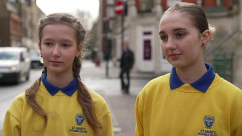 From left, Liza and Arina wearing yellow jumpers that read St Mary's Ukrainian School.