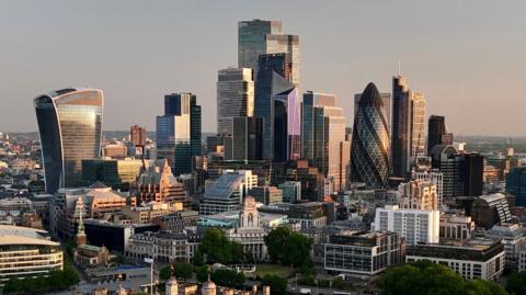 Day breaks over the City of London, with buildings visible including the Walkie Talkie and the Gherkin.