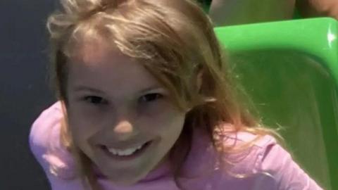Lilia Valutyte smiling at the camera with blonde hair and a pink top on.