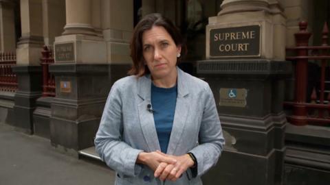 BBC correspondent Katy Watson standing outside the Supreme Court of Victoria. She is wearing a dark blue top and light blue blazer