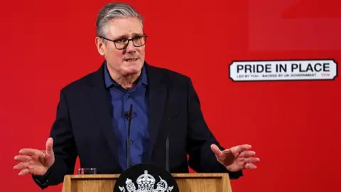 Keir Starmer standing behind a wooden lectern deliverin a speech