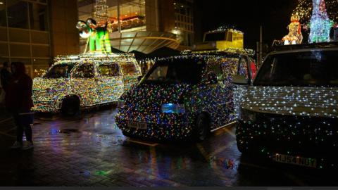 Three lit-up Volkswagen vans and one with Gromit on top, outside Cribbs Causeway Shopping Centre