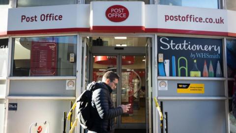 A man walks past a Post Office branch