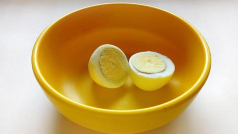 A boiled egg placed in a yellow plastic bowl