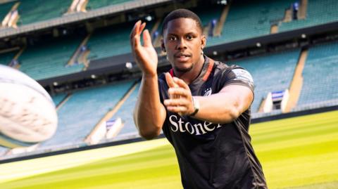 Maro Itoje passes the ball wearing a Saracens shirt