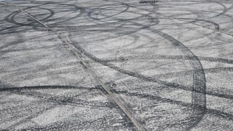 Tyre marks in a car park that look as though they were made by motorists doing doughnuts.