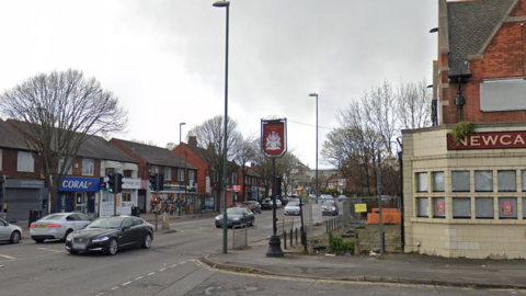 A general view of Nuthall Road, Nottingham, with cars driving along the road and shops in the background.