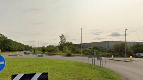 A streetview image of Meridian Way Braunstone, showing a road with roundabout and a large industrial building