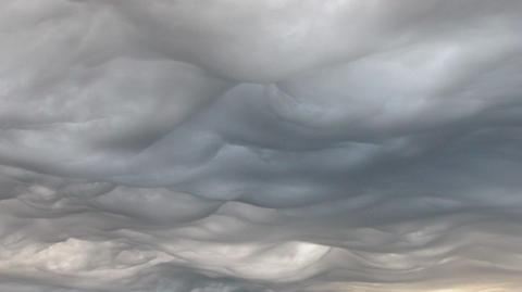 Image of a wide sky with heavy, undulating cloud over a landscape