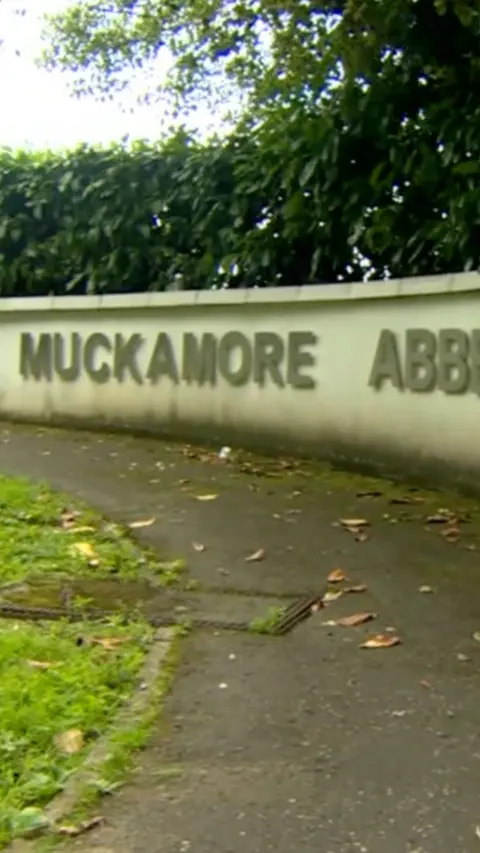 A wall with Muckamore in silver lettering on it. 