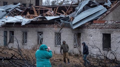 Residents walk at a site of a Russian missile strike, amid Russia's attack on Ukraine, in Dnipro