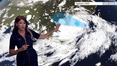 Elizabeth Rizzini in front of a ˿ Weather map showing the track of the typhoon