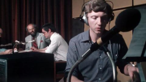 People sit at microphones in the Radio Foyle radio studio.